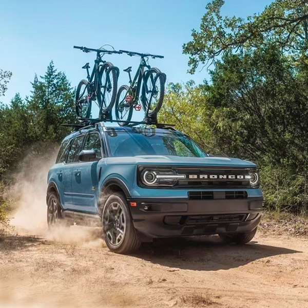 2024 Ford Bronco Sport driving through dirt road with bikes on roof rack