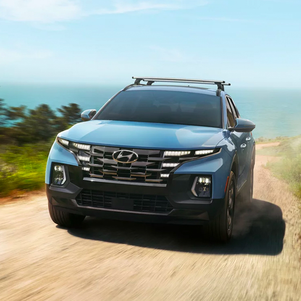 2024 Hyundai Santa Cruz driving along a rural seaside road.