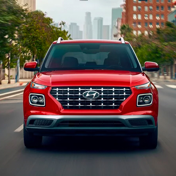 Front view of a red 2024 Hyundai Venue driving through the city