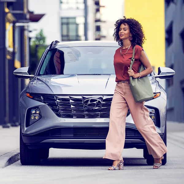 Stylish woman walking in front of a parked Hyundai Tucson