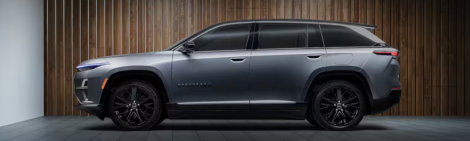 A driver-side profile of a silver 2024 Jeep Wagoneer S Launch Edition parked inside the garage of a contemporary home.