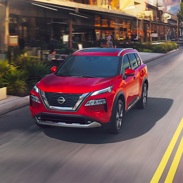 2025 Nissan Rogue driving through the city on a sunny day
