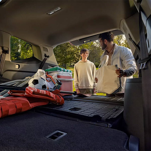 A father and son load sports equipment into the cargo area of an Atlas.