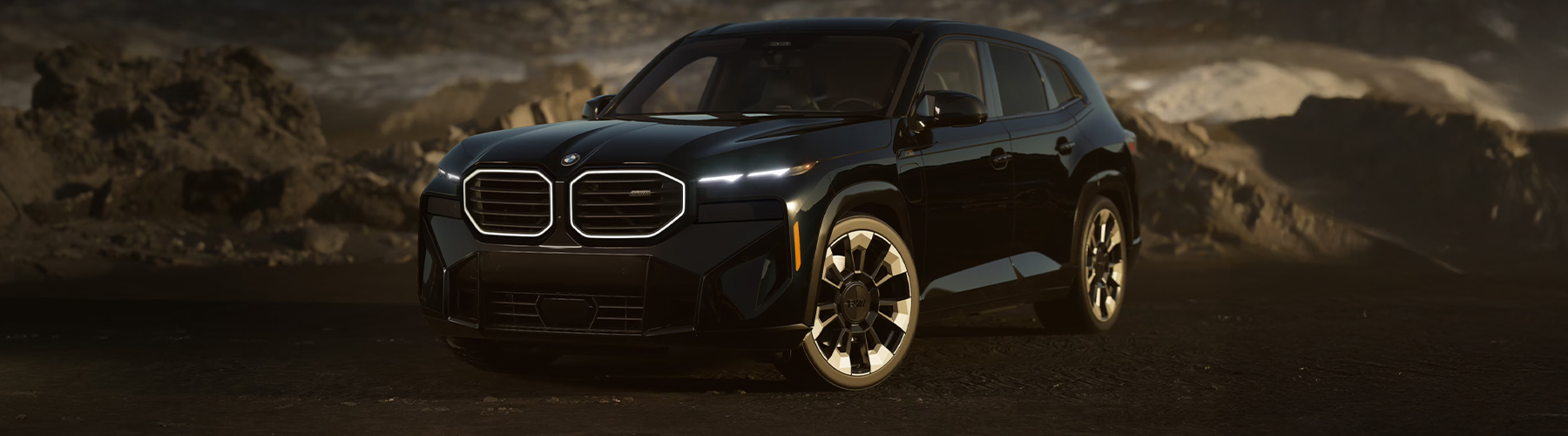 A front quarter shot of the BMW XM in Carbon Black Metallic paint finish, parked in a rocky, desert-like landscape