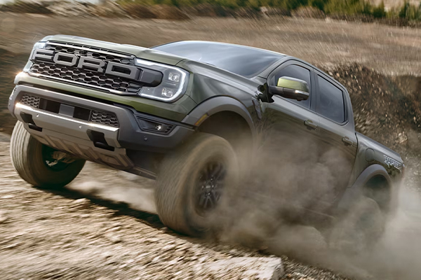 A 2025 Ford RangerĀ® RaptorĀ® in Shelter Green being driven on a rocky dusty trail