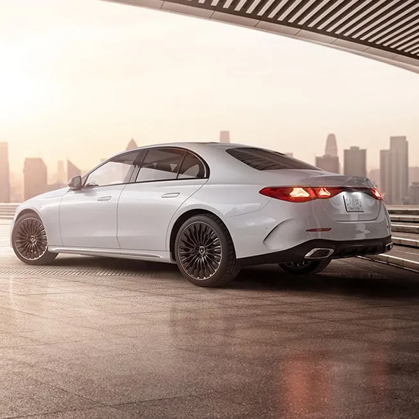 3/4 rear view of the 2025 Mercedes-Benz E Class parked with a city skyline in the background