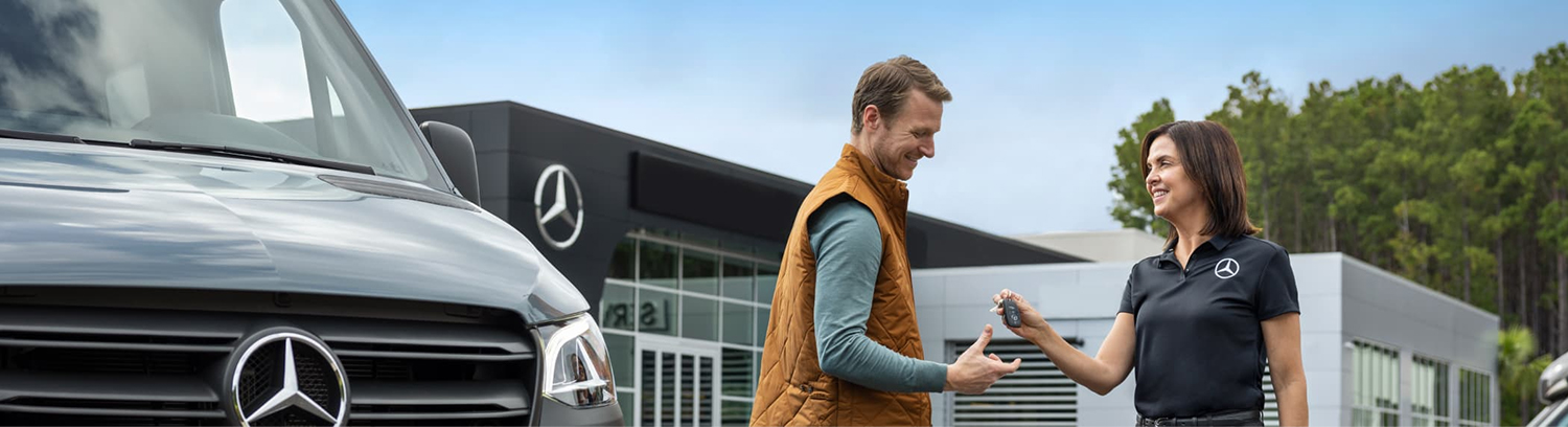 Dealership employee handing a customer the keys to their Van
