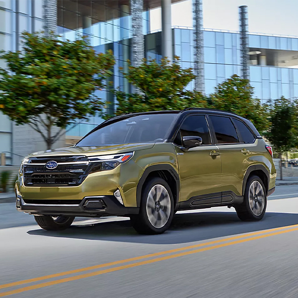 2025 Subaru Hybrid SUV driving in front of office building
