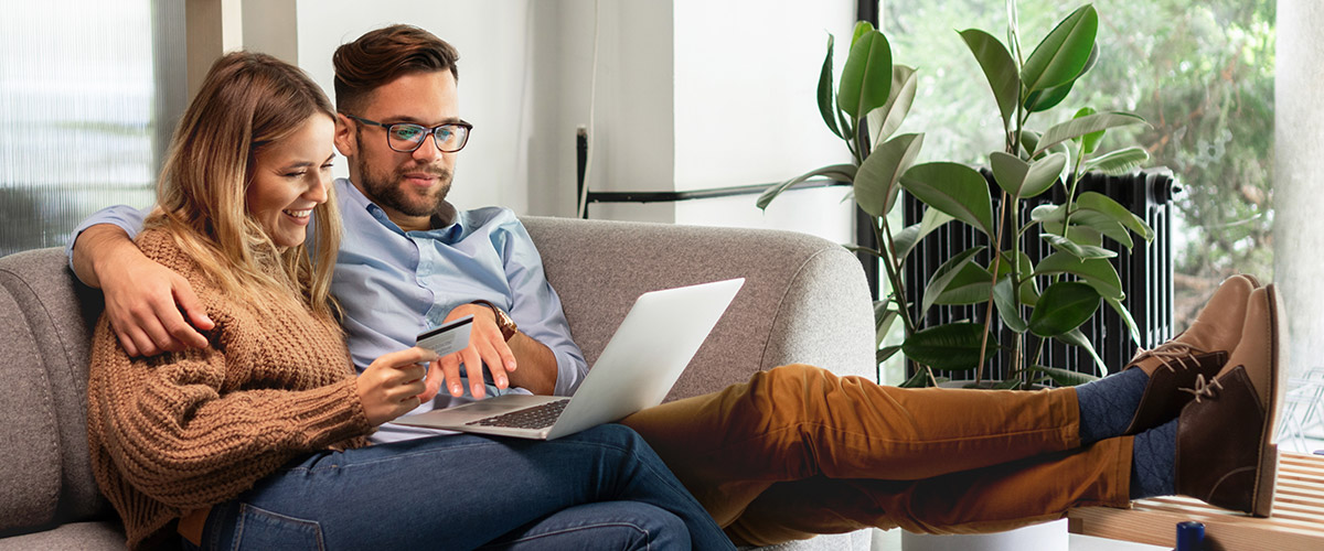 Happy couple on couch looking at laptop