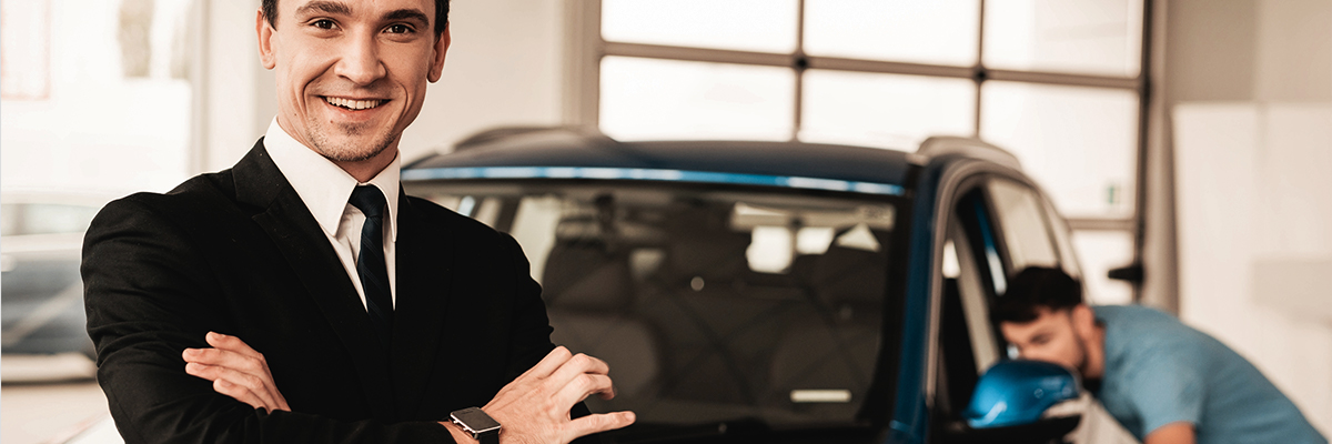 Portrait of two happy car sales consultants working inside vehicle showroom.