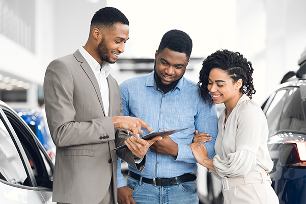 Salesman Offering Couple A Car Standing In Auto Rental Office