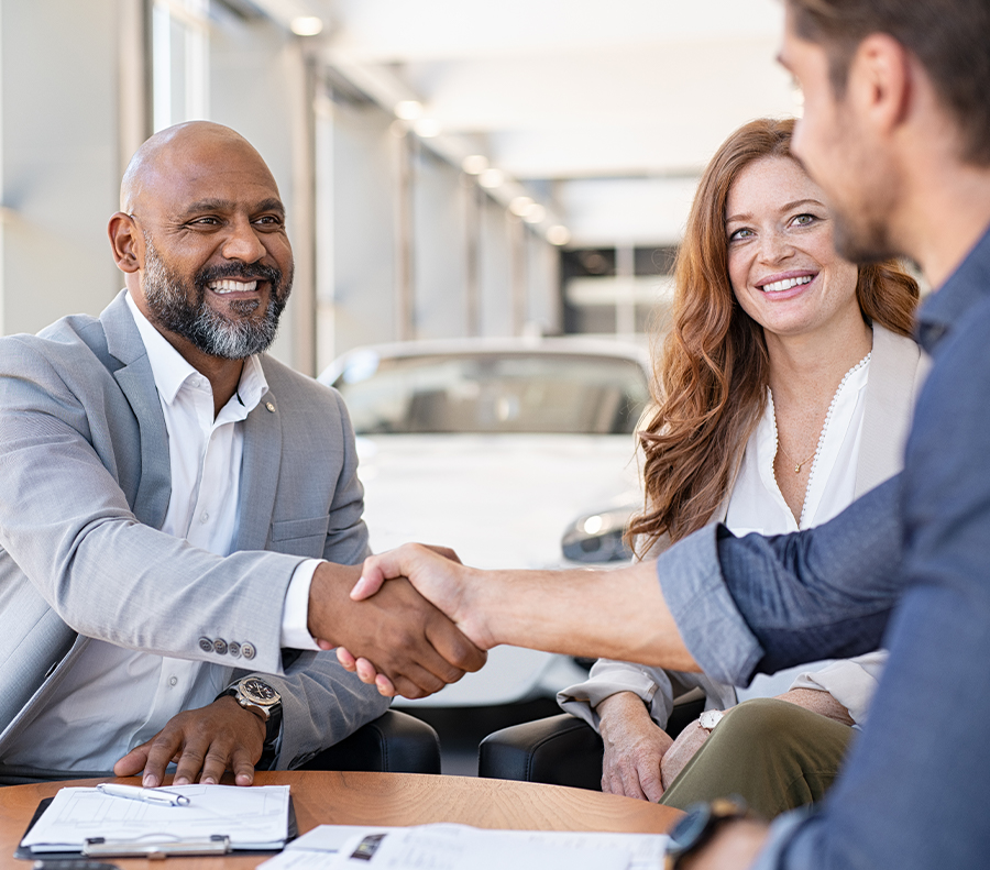 Smiling dealership employee shaking hands with satisfied customer