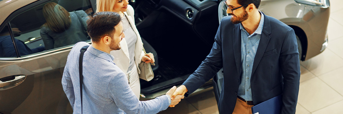 A couple smiling at salesman while shaking hands