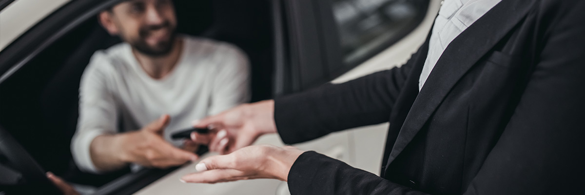 Someone handing car keys to someone in a car