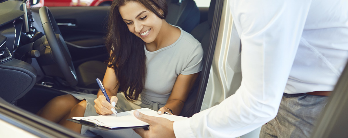 A young woman buys a car in a car showroom.