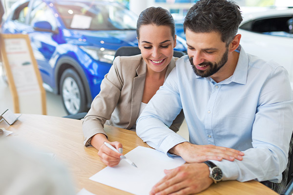 Young couple with car dealer in signing lease