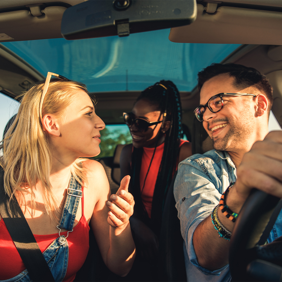 Group of happy friends riding in a car