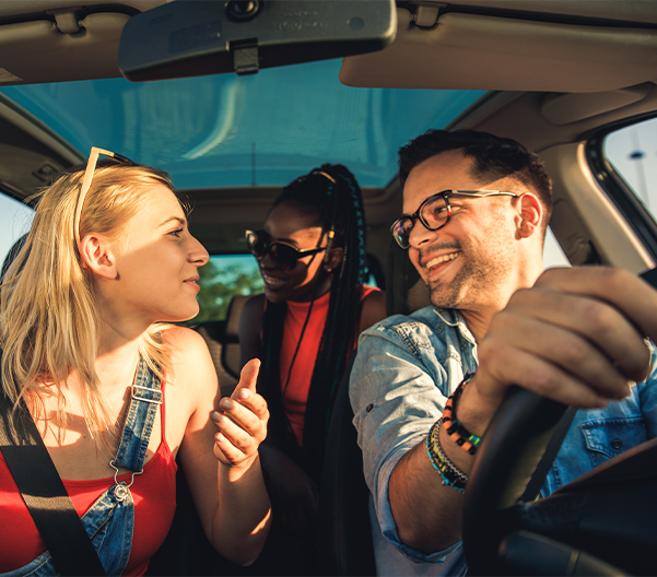 Group of happy friends riding in a car