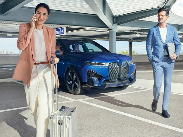A couple in business attire walk away from a BMW iX xDrive50 in a parking garage