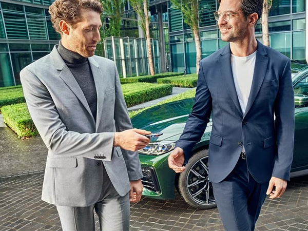 Two sharply-dressed men walk away from a parked BMW sedan