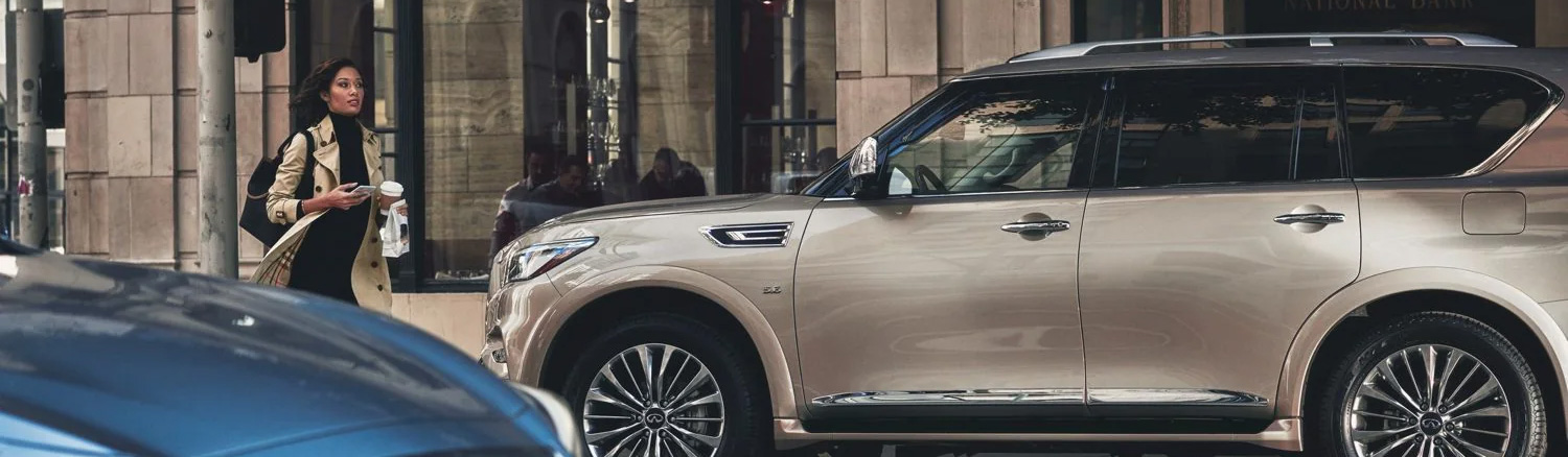 Stylish woman walking by an INFINITI SUV