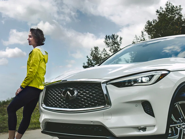 Active woman leaning up against an INFINITI vehicle