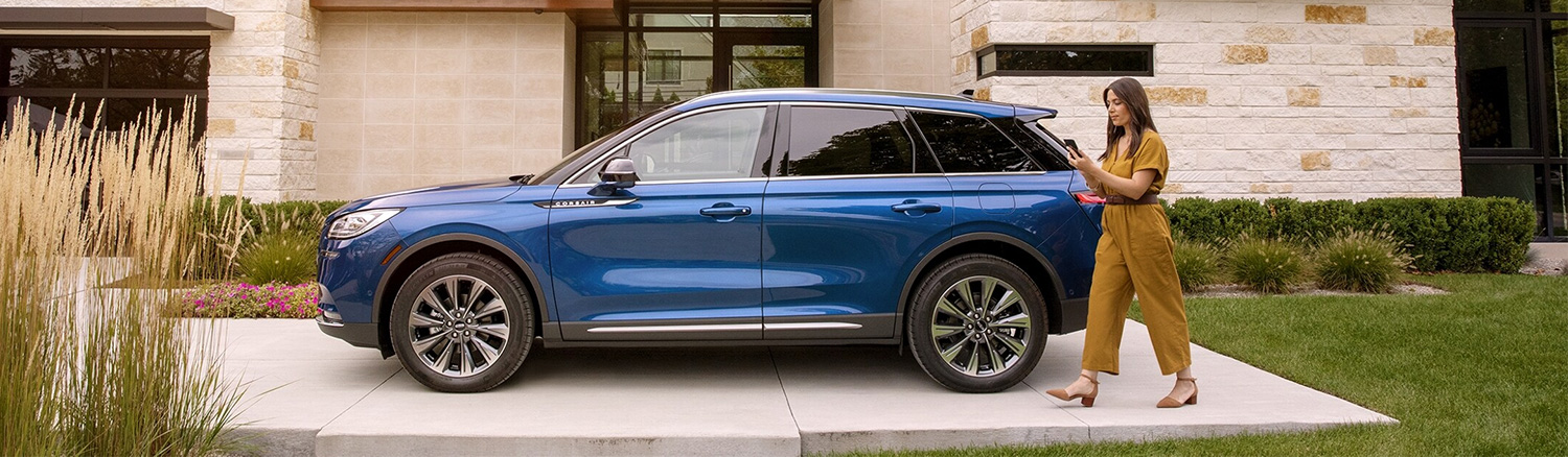 Stylish woman walking beside her blue Lincoln SUV