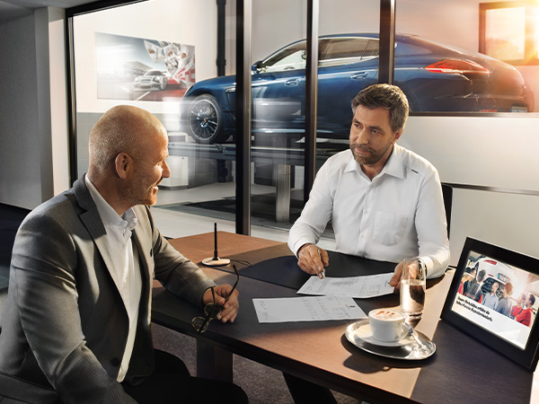 Dealership employee speaking with customer at a desk