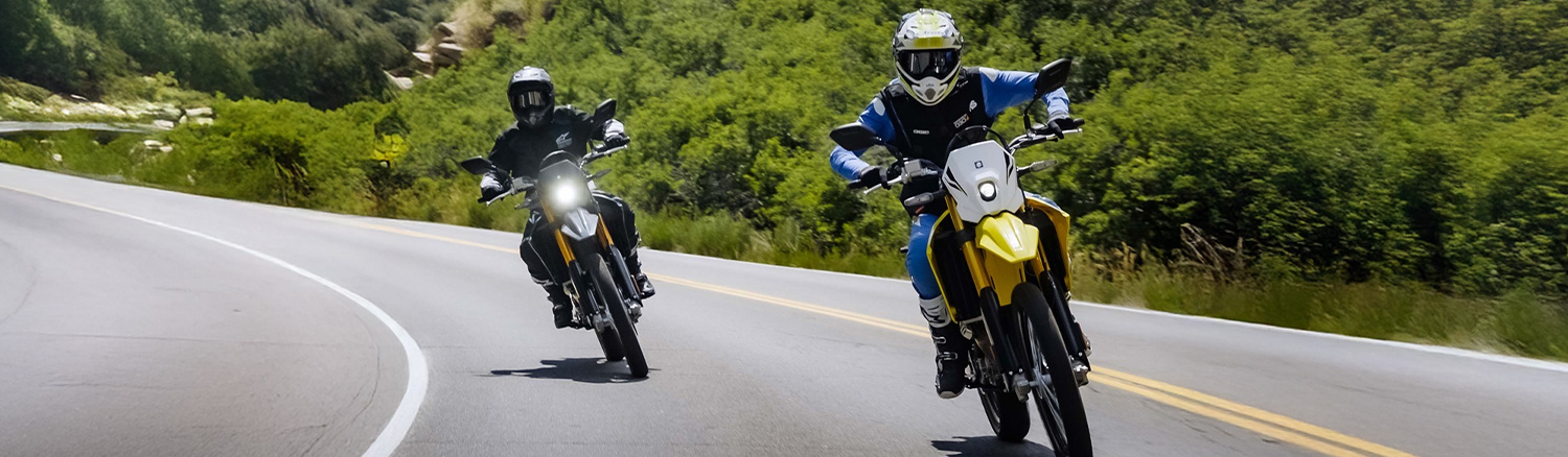 Two motorcycles driving down the road