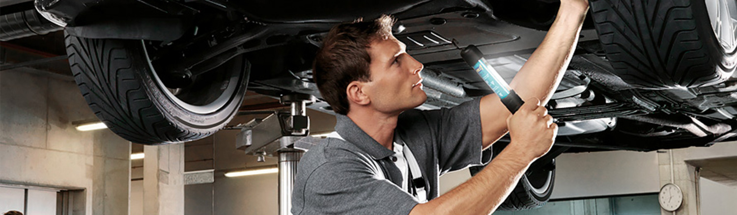 BMW service tech looking under a vehicle