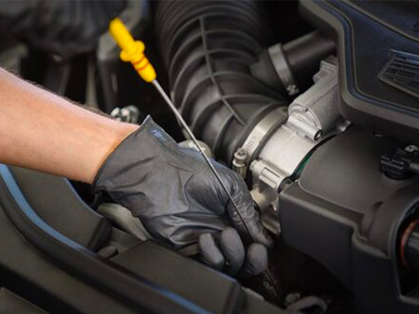 Service tech pouring oil into a vehicle for an oil change