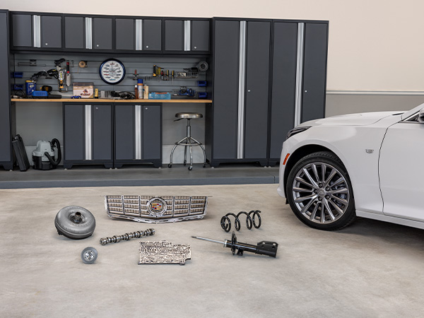 Cadillac vehicle in the service bay with parts on the floor beside it