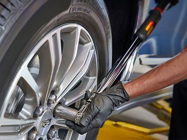 Service tech tightening a lug nut on a Cadillac tire