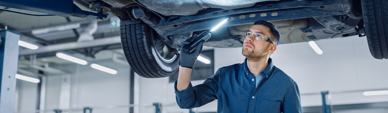 Technician using an inspection light underneath a vehicle