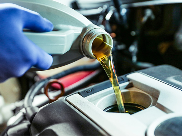 Service tech pouring oil into a vehicle for an oil change