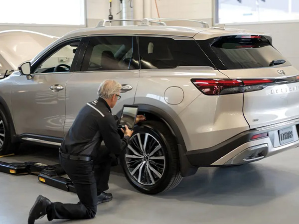 INFINITI service tech inspecting the tires on an SUV