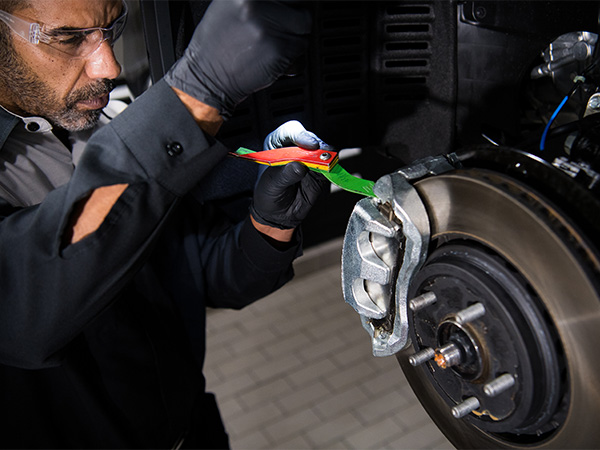 Lexus service tech inspecting a vehicle's brakes with a light