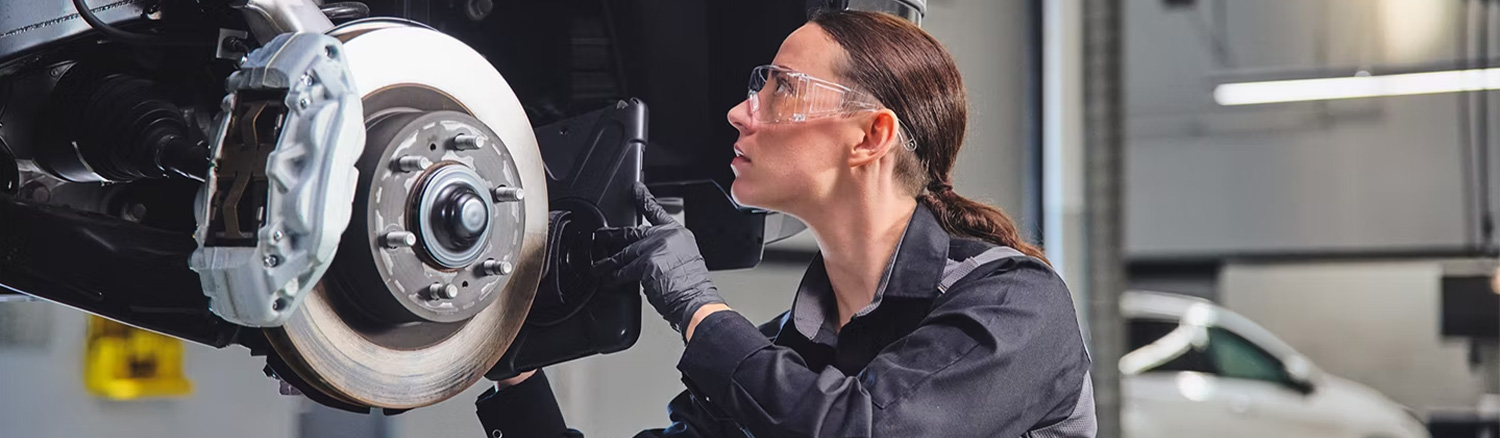 Lexus service tech inspecting brakes on a vehicle