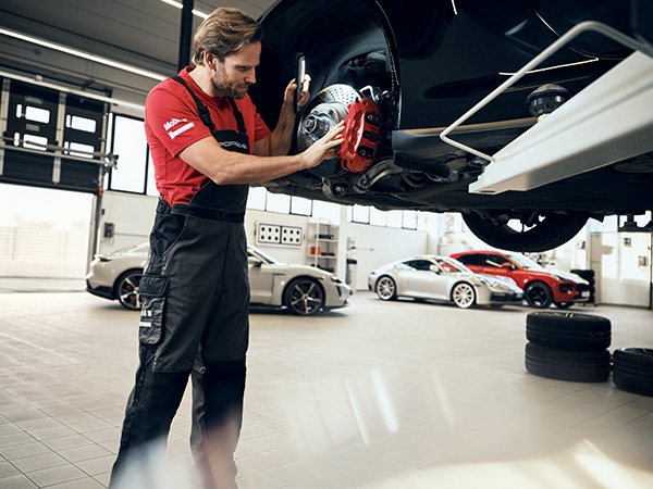 Porsche service member looking at the brakes