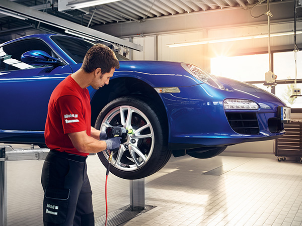 Service tech putting a tire back on a Porsche