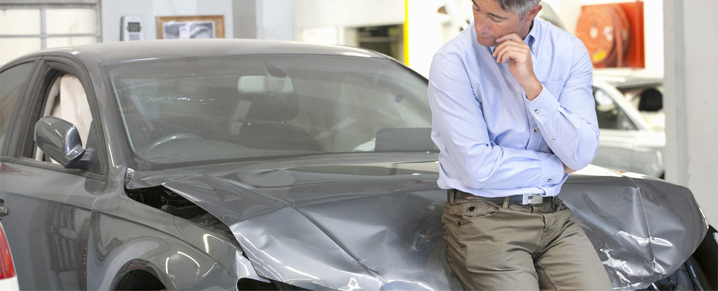 Man leaning up against a damaged ford vehicle