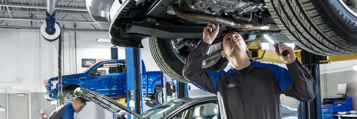 Ford Repair man working on underside of car