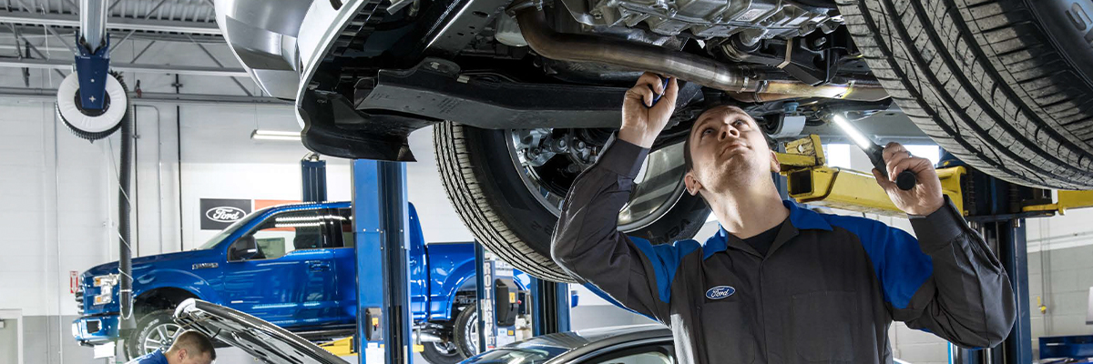 Ford service tech under a vehicle