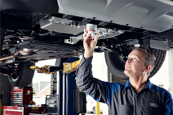 Ford service tech under a vehicle