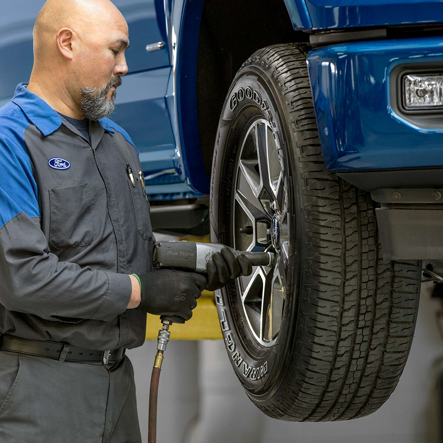 Ford service tech tightening bolts on a tire