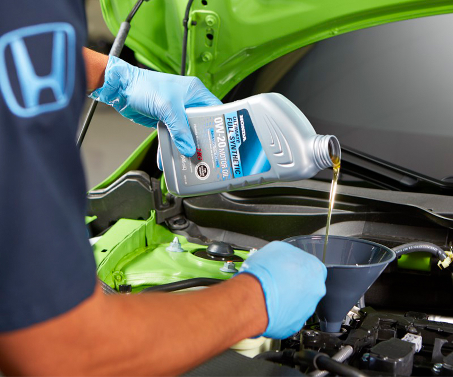Honda technician pouring oil into a car