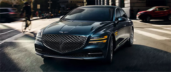 3/4 front view of the 2024 Genesis G80 driving through the city