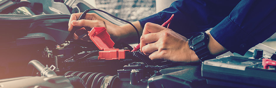 auto technician checking battery life with battery tester