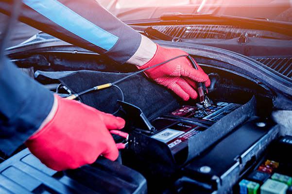 auto technician transferring light current to a car battery