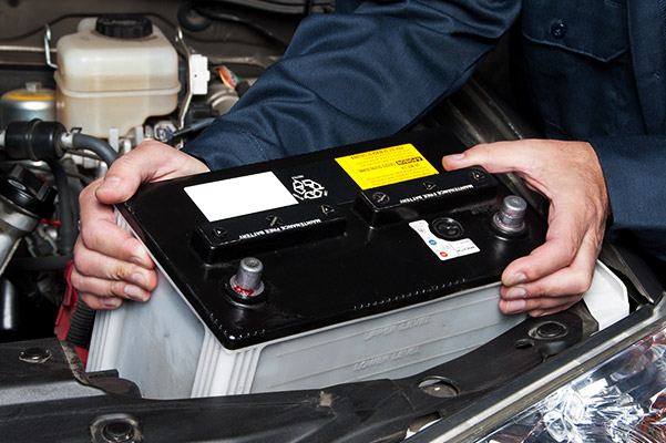 auto technician installing a new car battery on a car